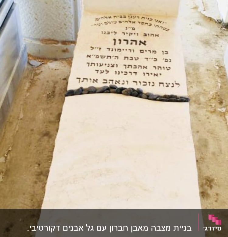 מצבה עם כיתוב בעברית ואבנים קטנות מונחות עליה